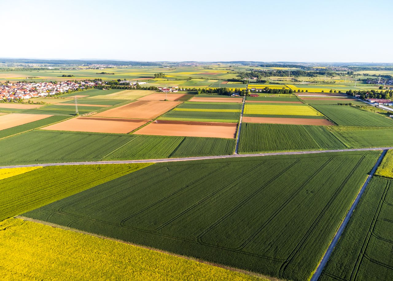 Stunning aerial view of vibrant patchwork agricultural fields and a distant village.