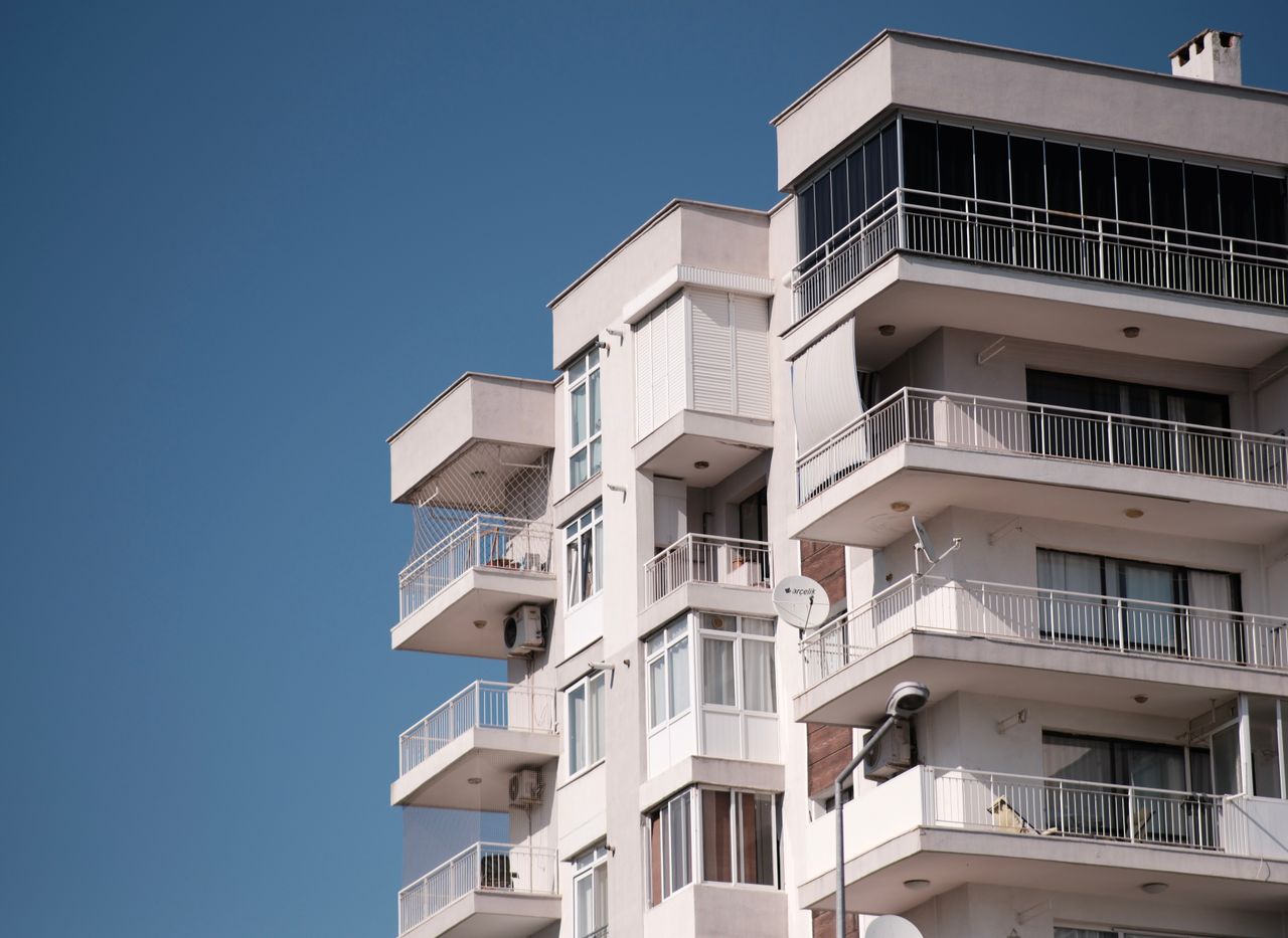 Contemporary apartment building in İzmir under clear blue sky, showcasing modern architecture.
